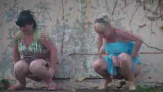 2 Russian women peeing behind shed